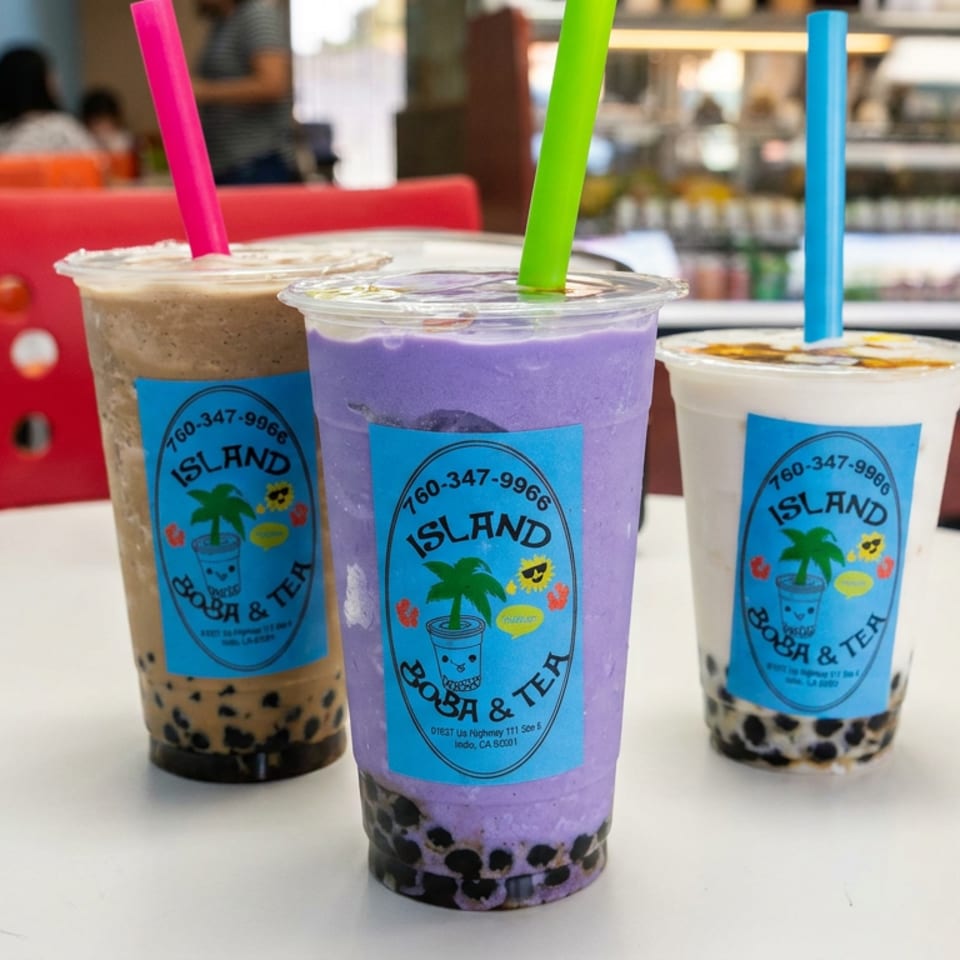 Three colorful Island Boba & Tea drinks with tapioca pearls and bright straws arranged on a café table.